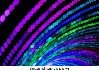 A tunnel of multi coloured lights lit up at night in an intentional out of focus shot to create circular strings of bokeh. - Powered by Shutterstock