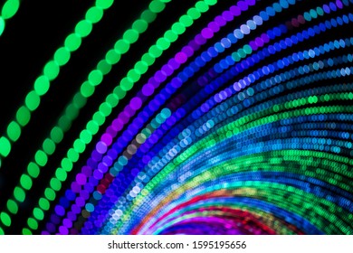 A tunnel of multi coloured lights lit up at night in an intentional out of focus shot to create circular strings of bokeh. - Powered by Shutterstock