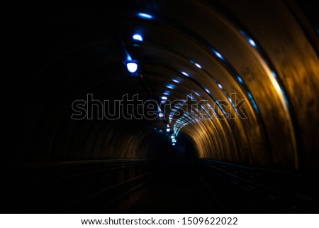 Tunnel overpass at night. Dark lighting inside the tunnel. Glare on the glass surface from the lamps. Night walk in sleeping areas. Darkness is fraught with danger.