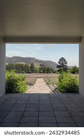 Tunnel through a building with access to a courtyard, garden, outside. Nature of South Africa. View of nature through the frame. Walking paths, vegetation and bushes with green leaves