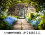 Tunnel of trees and flowers in front of garden gate in old mansion, Preston Manor Garden, Brighton, East Sussex, UK