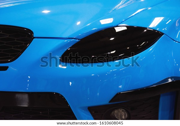 Tunning car detail. Close-up detail of one of the\
headlights of super car. Luxury blue car headlight close up.\
Concept of expensive, sports auto. The concept of tuning. Black car\
head lights.