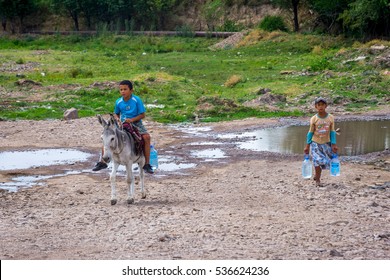 TURBAT, KAZAKHSTAN - JULY 21: Two Kids Carrying Plastic Bottles Of Water At The Spring By Donkey. July 2016