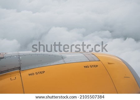 Turbine of airplane during a flight. Aircraft engine with dense white and gray clouds in the background. Part of plane with indications of 
