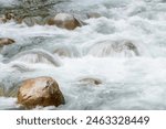 Turbulent clean river water crashes over smooth river rocks creating whitewater on descent