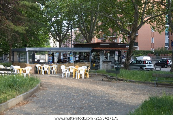 Turin, Italy - May\
5 2022: View of kiosk with drinks, coffee and beer as well as\
tables and chairs outside in the city park amidst greenery, not far\
from the road and parked\
cars