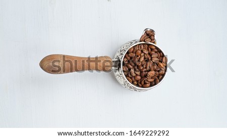 Turk with coffee beans on a white wooden background. Close up.