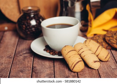 Turk for coffee in a mug, a spoon, a croissant on a saucer and sugar cubes on wooden background.