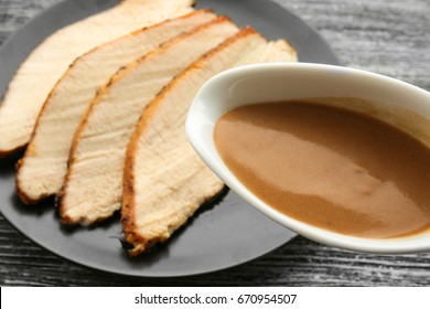 Turkey Gravy In Sauce Boat Over Plate With Sliced Meat On Table