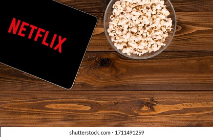 Turkey, Istanbul / April 2020 Apple tablet and popcorn in bowl on wooden floor. The logo of the Netflix platform, which broadcasts global movies and series on the tablet screen. Besides copy space.