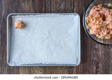 Turkey meatball mixture in a glass bowl, raw meatball on a parchment paper lined baking tray
