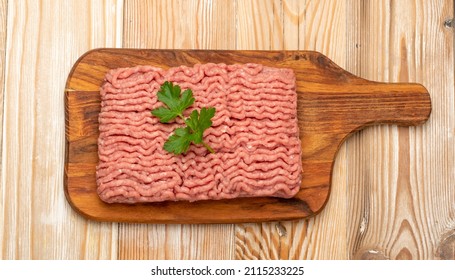 Turkey mince meat top view. Ground fillet on wood background, uncooked turkey mincemeat, raw forcemeat, fresh farce meat portion with greens top view