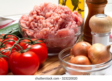 Turkey Mince, Tomatoes, Onions, Garlic, Olive Oil, Salt, Pepper And Cucumbers On A White Table