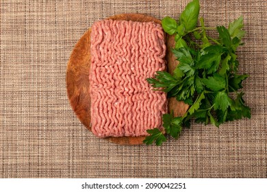 Turkey minced meat. Ground fillet on wood plate, uncooked turkey mincemeat, raw forcemeat, fresh farce meat portion with greens top view