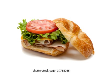 A Turkey Sandwich On A Croissant With Lettuce, Cheese And Tomatoes On A White Background