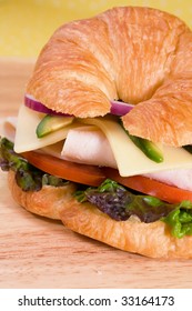 Turkey Sandwich On A Croissant With Swiss Cheese, Avocado, Tomatoes, Lettuce, And Onion.