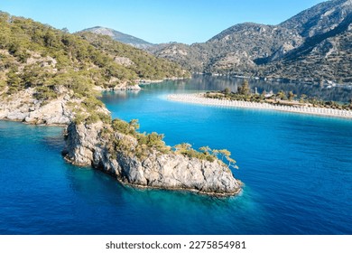 Turkey, scenic beach with white sand surrounded blue sea. Amazing aerial view on sea coast. Blue lagoon lost surrounded between high moutains. Sunny day in small town Oludeniz, Turkey.  - Shutterstock ID 2275854981
