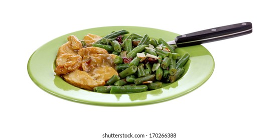 Turkey Tenderloin Slices In Gravy With Cut Beans, Cranberries, Slivered Almonds On A Green Plate With Fork On White. 