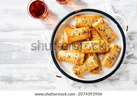Turkish borek rolls with spinach and cheese. A traditional Turkish pastry rulo borek with black and white sesame seeds. White  wooden background. top view