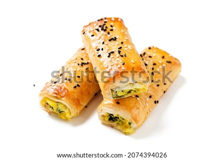 Turkish borek rolls with spinach and cheese. A traditional Turkish pastry rulo borek with black and white sesame seeds. Isolated on white background.