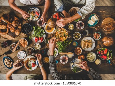 Turkish Breakfast. Flat-lay Of Family Eating Pastry, Vegetables, Greens, Cheeses, Fried Eggs, Jams From Oriental Tableware And Drinking Tea From Tulip Glasses Over Rustic Wooden Background, Top View