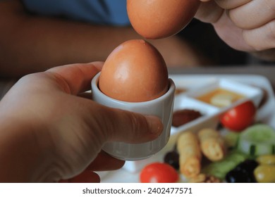 Turkish breakfast plate and two people's hands. a brown-shelled boiled egg placed in an egg cup. Breaking the shell of two boiled eggs by pressing them together. - Powered by Shutterstock