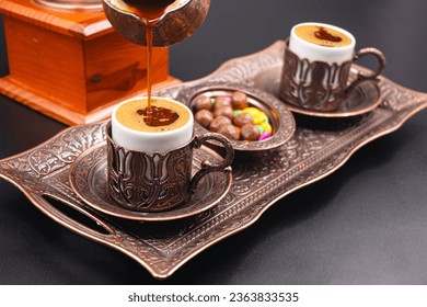 Turkish coffee in artistic cup, coffee grinder in background and cooked Turkish coffee pouring from coffee pot into cup. Photograph. - Powered by Shutterstock