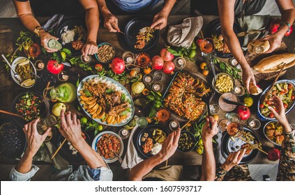 Turkish cuisine family feast. Flat-lay of people celebrating with lamb chops, quince, bean, salad, babaganush, rice pilav, pumpkin dessert, lemonade over rustic table, top view. Middle East cuisine