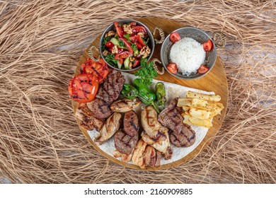 Turkish cuisine, mixed kebab. Meat platter fried on charcoal with spices on a wooden board. Rack of lamb, lamb, kebab, chicken, mushrooms and tomato sauces for meat.
