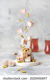 Turkish delight levitation flying photo. Sweet Lokum with pistachio nuts and tea cups. Vertical food photo. Creative concept  - Shutterstock ID 2020450697