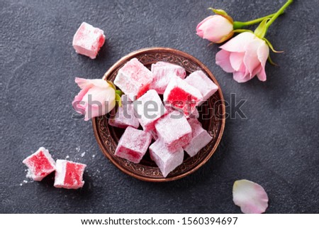Turkish delights lokum, rose flavour in a copper plate. Dark background. Top view.