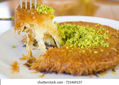 turkish dessert kunefe, kunafa, kadayif with pistachio powder and cheese hot eaten a sweet