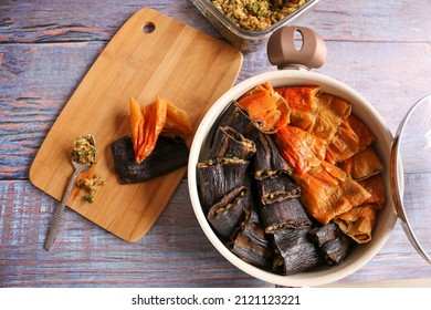 Turkish dolma, preperation of turkish traditional food. Local name is dolma. Cooking and kitchen concept,idea. Selective focus on aubergines. Old blue wooden background.