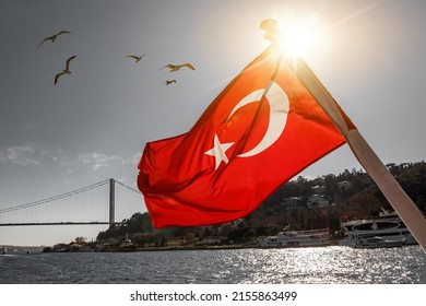 The Turkish flag waving over the Bosphorus. Istanbul Bosphorus bridge, July 15 bridge in the background - Shutterstock ID 2155863499