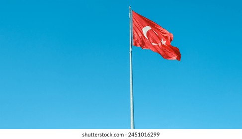 Turkish flag waving in the wind on the flagpole against blue sky background. Turkish flag photo for Turkish national days celebration.