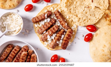 Turkish flatbread with minced meat cevapi with sliced onions and cherry tomatoes, top view