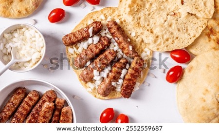 Turkish flatbread with minced meat cevapi with sliced onions and cherry tomatoes, top view
