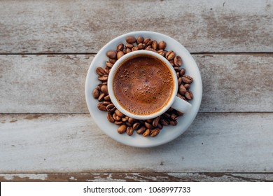 Turkish or Greek Coffee in circle shaped surrounded with roasted coffee beans on white rustic wooden table from top view. Traditional tasty refreshment coffee