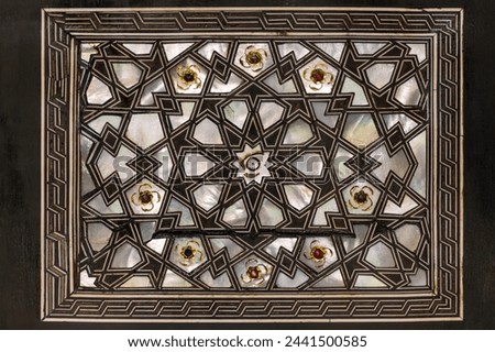 Turkish Islamic art of mother-of-pearl inlay with dark geometrics and jewel accents.
