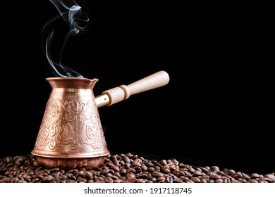 Turkish Jezve Coffee Pot with hot coffee at coffee beans background