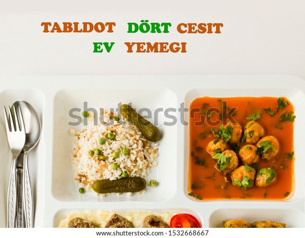 Turkish meal in white color portion food tray,on\
the white surface.Writing on image:Tabldot four types of homemade\
foods with Turkish\
Letters.