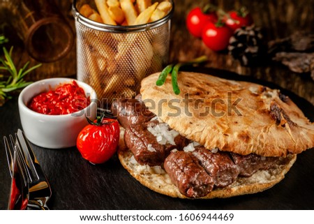 Turkish, oriental cuisine. Turkish tortilla, bun, pita bread with kebab and pickled onions. Serving in a restaurant on a black slate, on wooden table. background image, copy space