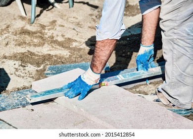 Turkish Pavement Construction Worker Using A Water Level Tool For Balancing The Tiles.