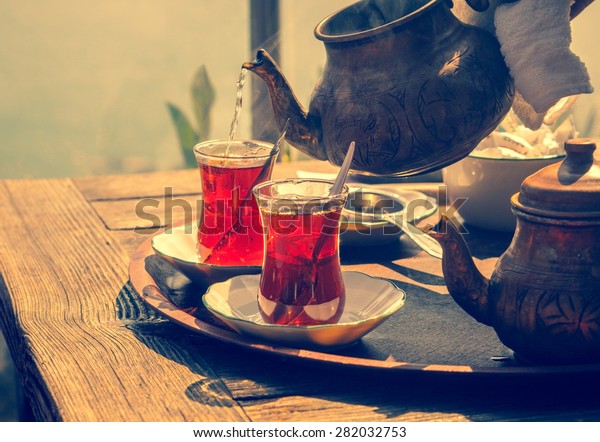 Turkish\
tea with authentic glass cup and copper tea kettle. Two cups of\
turkish tea,  toned with vintage instagram filter effect. Istanbul\
cafe with oriental culture of the street\
food.