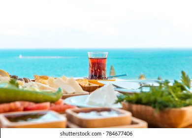 Türkischer Tee mit Frühstück auf dem Tisch vor Meereshintergrund in der Sommersaison. Türkisches oder griechisches Frühstück am Meer. Dieser türkische Tee ist rot. Urlaub in der Türkei oder Griechenland