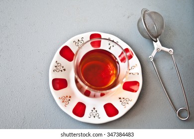 Turkish Tea In Traditional Glass And Tea Strainer On A Light Gray Background. Top View