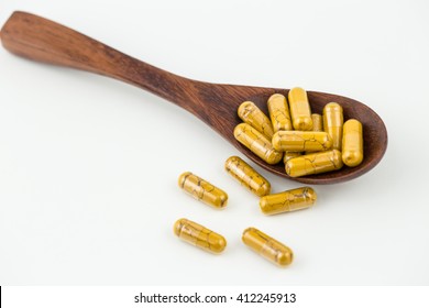 turmeric capsules on wooden spoon, Medicinal Used : Fresh and dried rhizome : treatment of peptic ulcer, dyspepsia, indigestion, flatulence; contain volatile oil, curcumin.