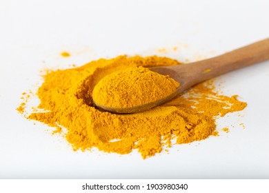 Turmeric or curcuma powder. Turmeric powder in a wooden spoon lay flat isolated over white background.