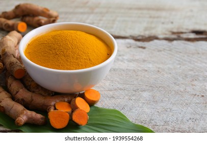 Turmeric (curcumin) Powder In A White Bowl And Turmeric Root On A Wooden Table,copy Space.