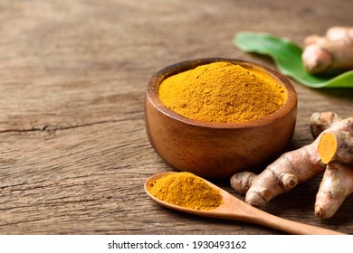 Turmeric (curcumin) Powder In Wooden Bowl With Fresh Rhizome On Wood Background.